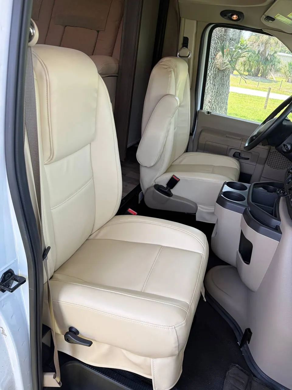 Reupholstered cream RV cab captain's chairs installed in a Class C motorhome
